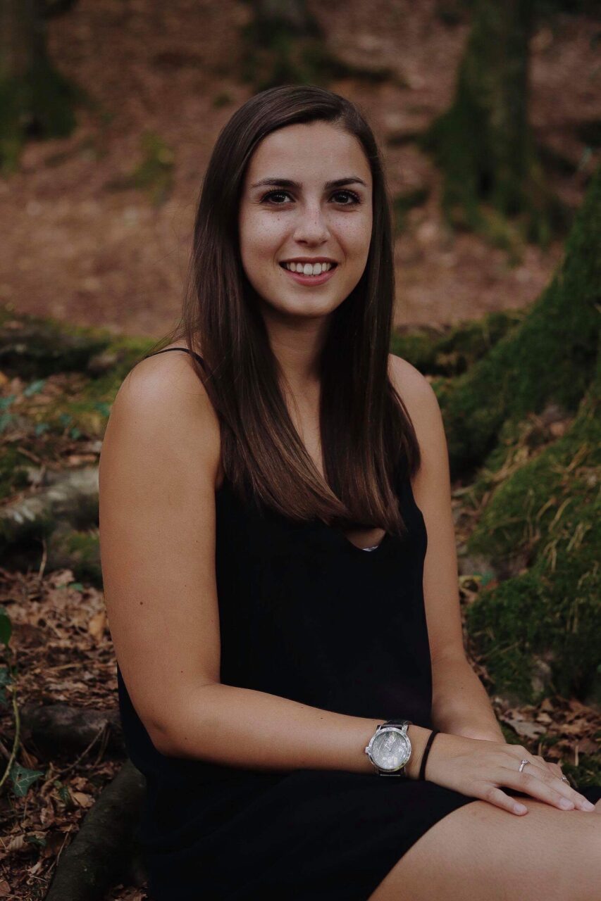 Caroline Mertz en robe noire, assise au pied d’un arbre (2018)