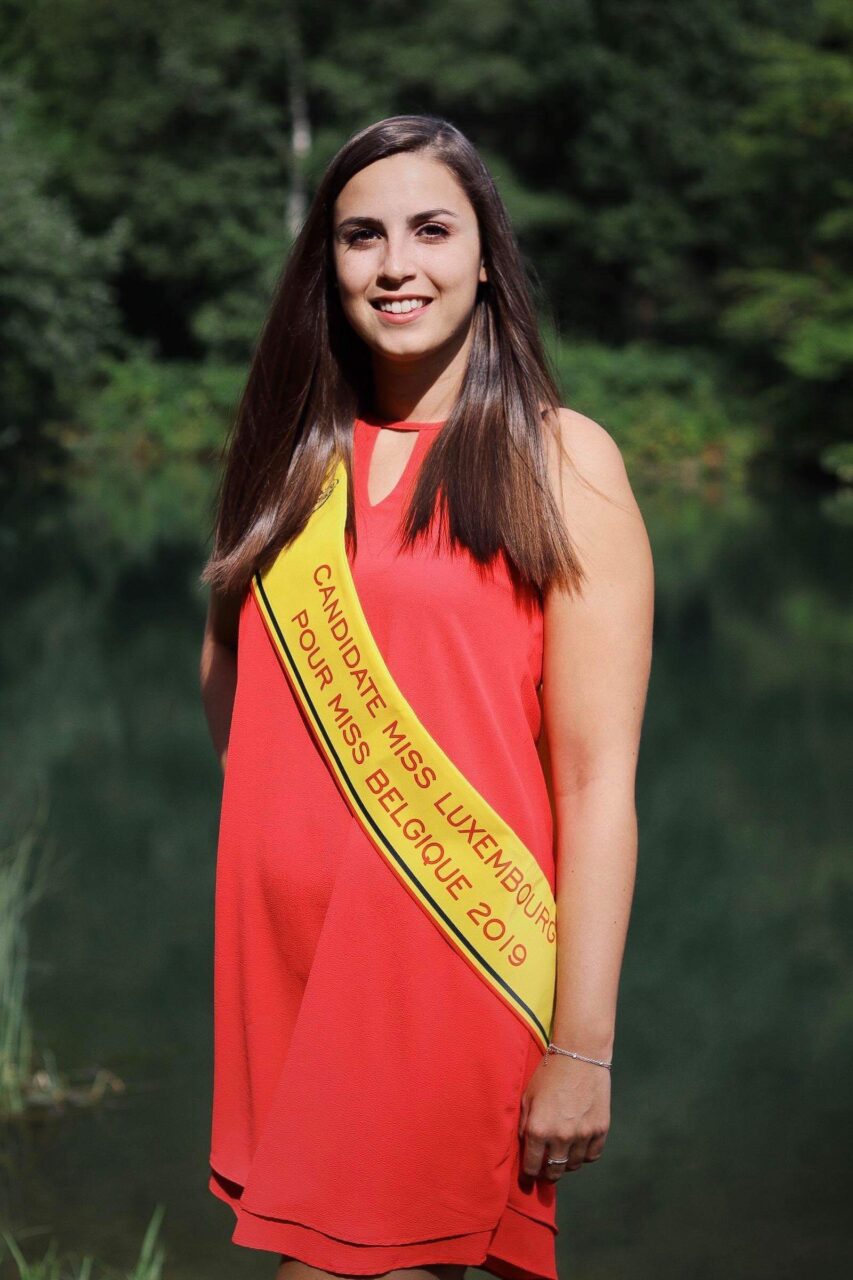 Caroline Mertz en robe corail et écharpe de candidate, au bord de l’eau (2018)