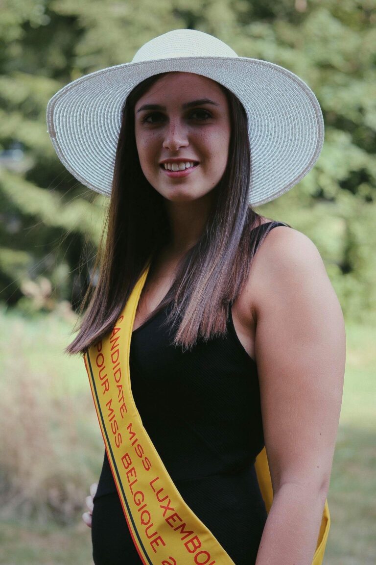 Caroline Mertz en chapeau blanc et robe noire, avec son écharpe de candidate (2018)