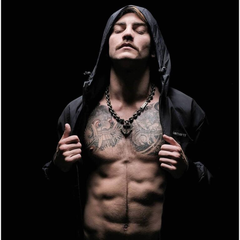 Marc Roger, capuche noire sur un torse tatoué, en studio