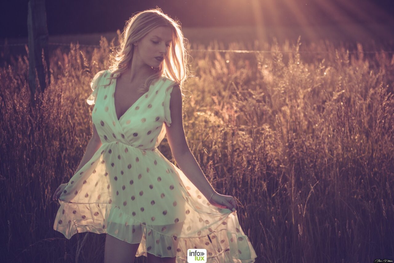 Claudia Stella en robe verte à pois, à contre-jour dans un champ
