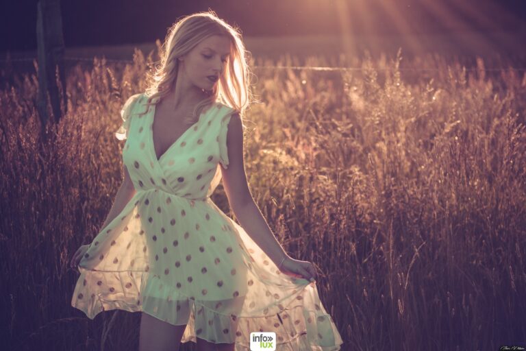Claudia Stella en robe verte à pois, à contre-jour dans un champ