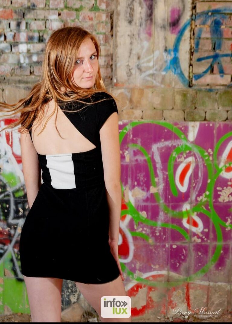 Laura Vervekken en robe noire, devant un mur de graffitis