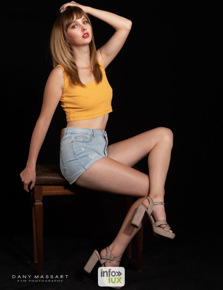 Aurélie Duchatelet en top jaune, assise sur une chaise, en studio