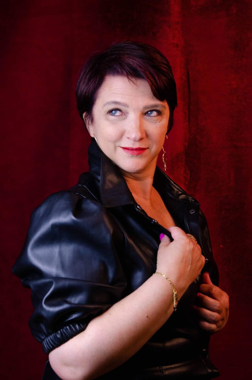 Véronique en veste de cuir noir, sur fond de velours rouge