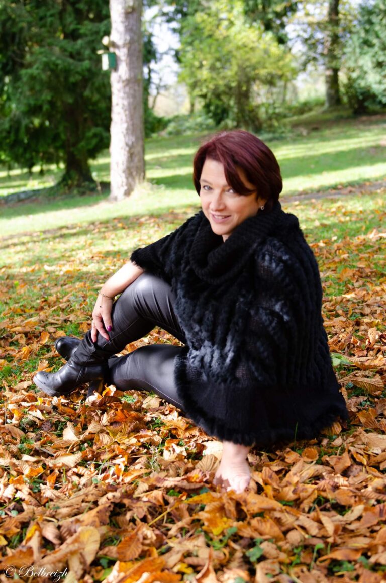 Véronique assise dans l’herbe et les feuilles, souriante
