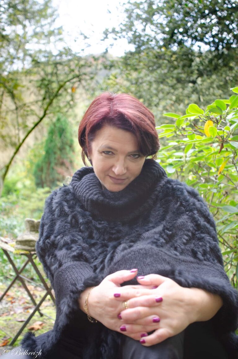 Véronique en poncho de laine grise, au jardin
