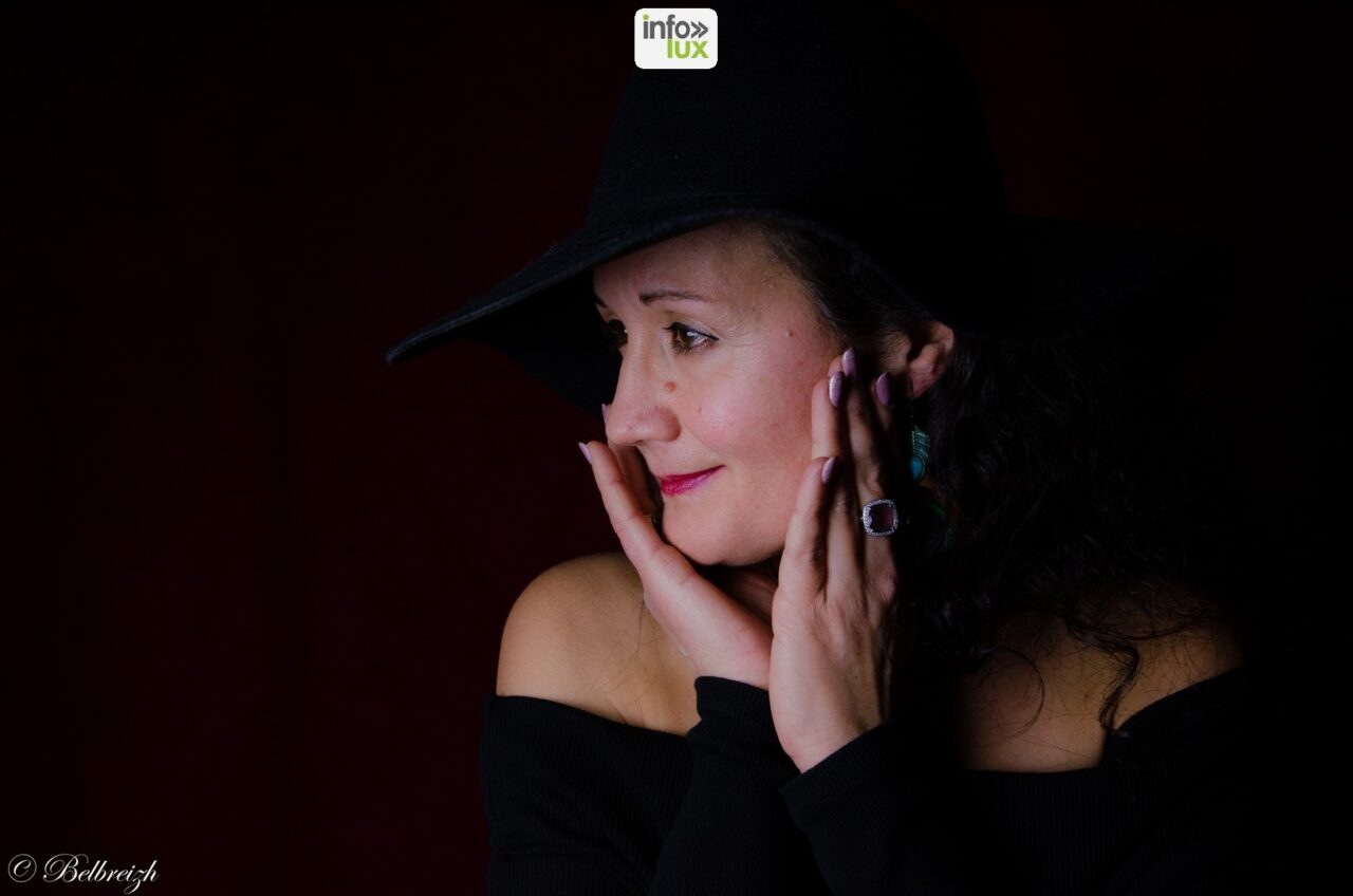 Marysa sous un grand chapeau noir, les mains sur le visage