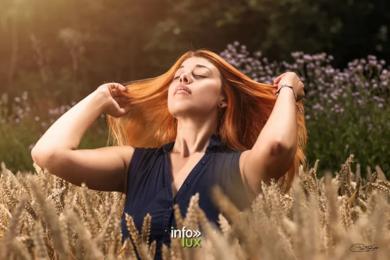 Juliette, les mains dans les cheveux, dans un champ de blé
