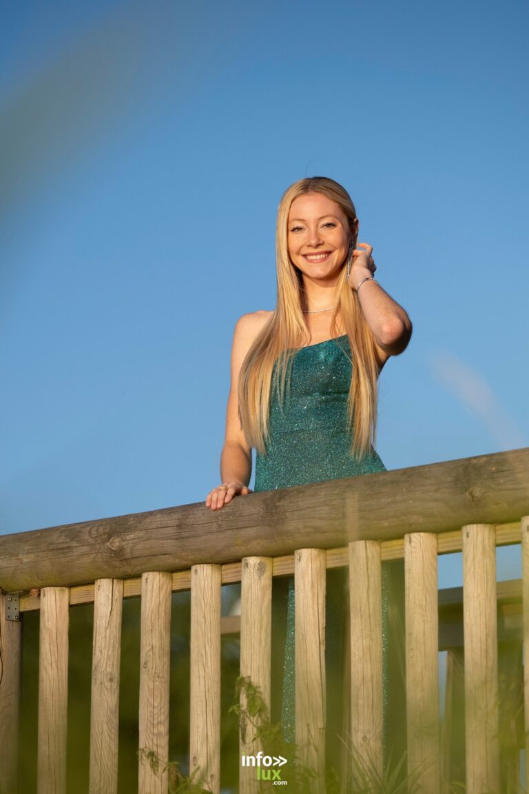 Margot Grivel en robe verte, la main dans les cheveux, sous un ciel bleu