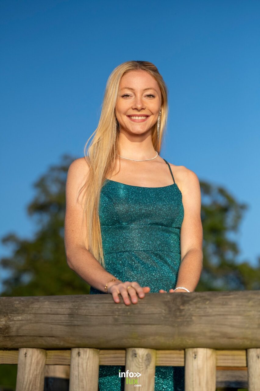 Margot Grivel en robe verte pailletée, accoudée à une barrière de bois