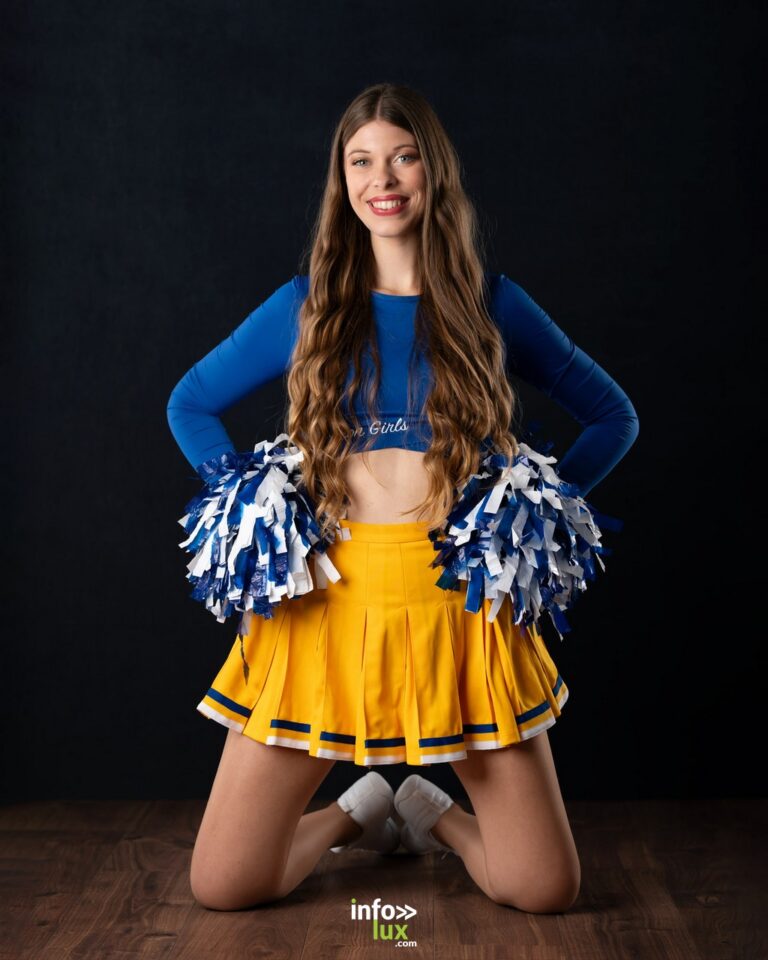 Célia Zimmermann à genoux, pompons en main, en tenue de cheerleader