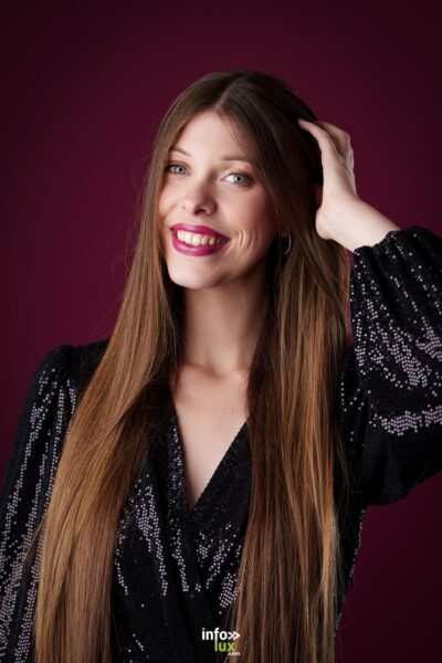 Célia Zimmermann, main dans les cheveux, sur fond pourpre