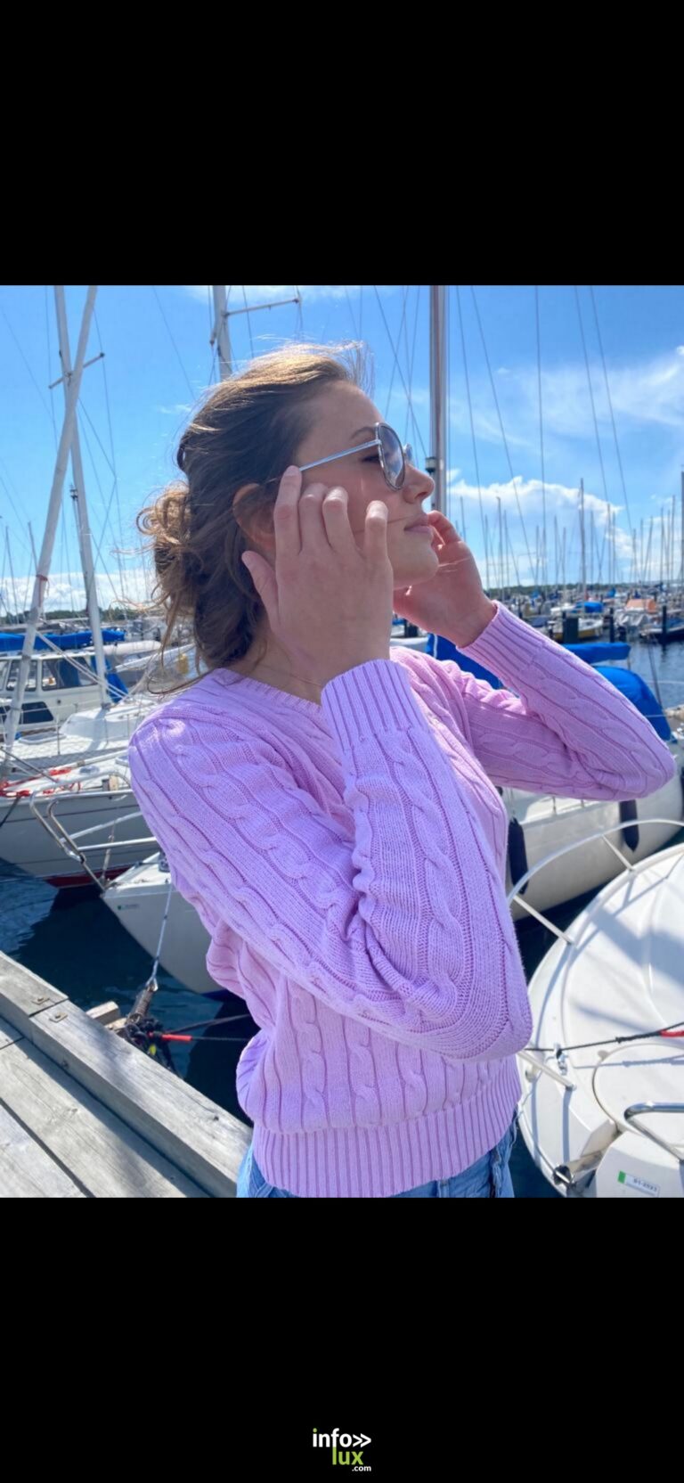 Estelle Heine en pull mauve, lunettes de soleil, sur un ponton de port de plaisance
