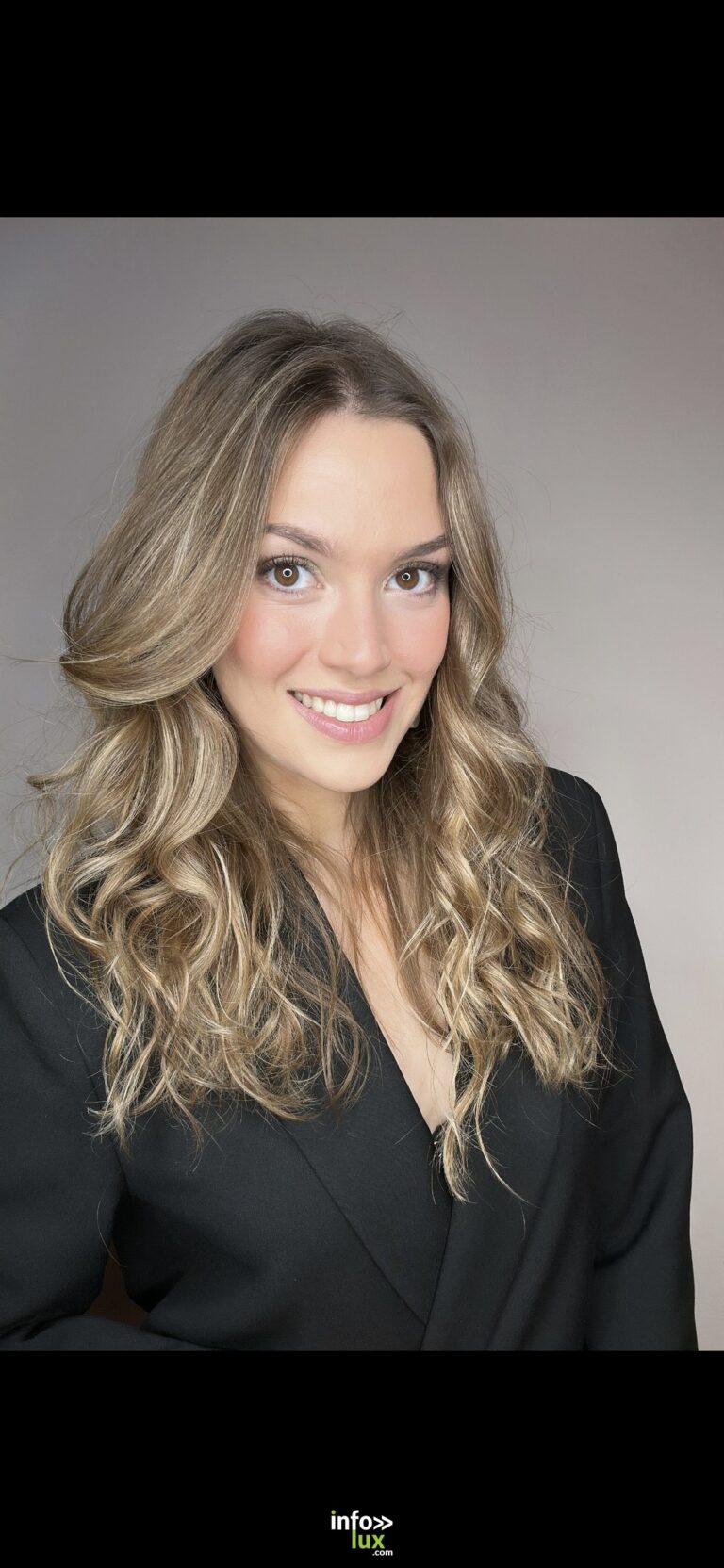Estelle Heine en veste noire, sourire, sur fond gris
