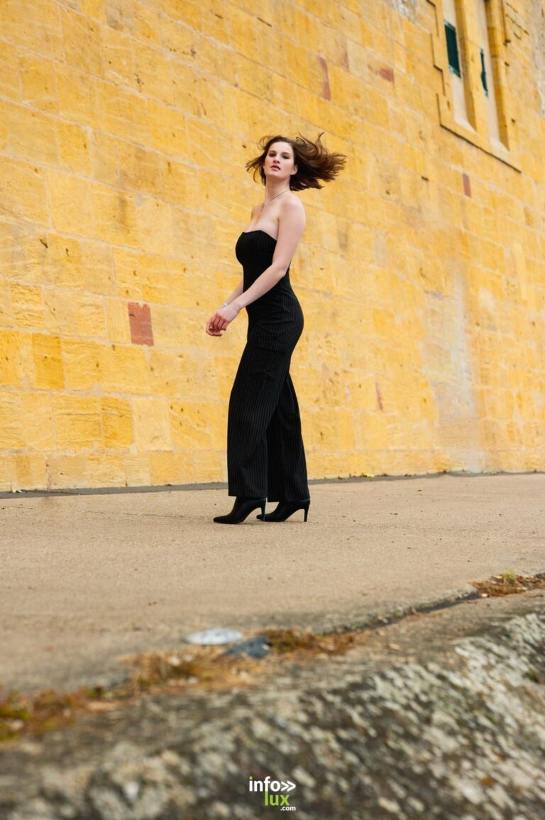 Léanne Stéphano en combinaison noire, le long d’un mur de pierre jaune