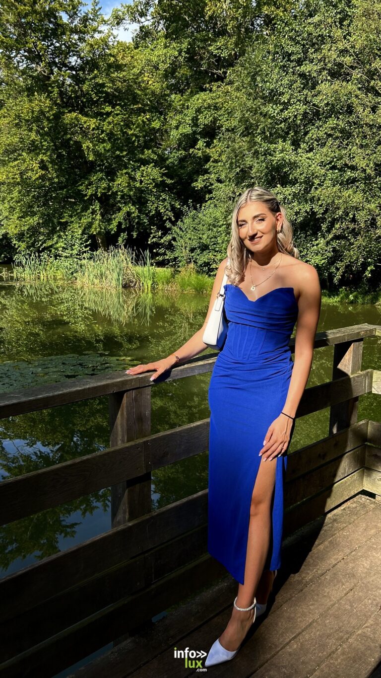 Carla Mastrorillo en robe bleue fendue, sur un ponton au bord de l’eau
