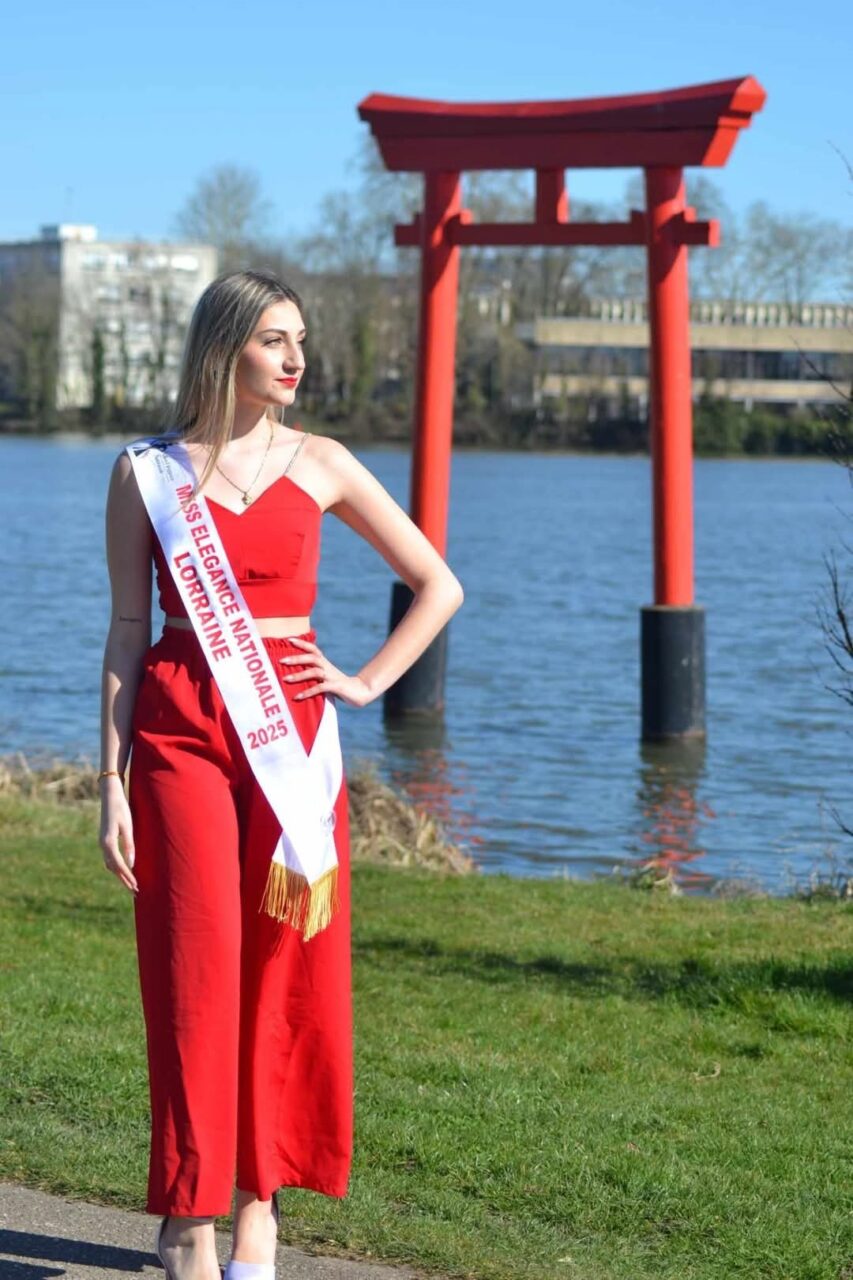 Carla Mastrorillo en ensemble rouge et écharpe de Miss, devant un torii