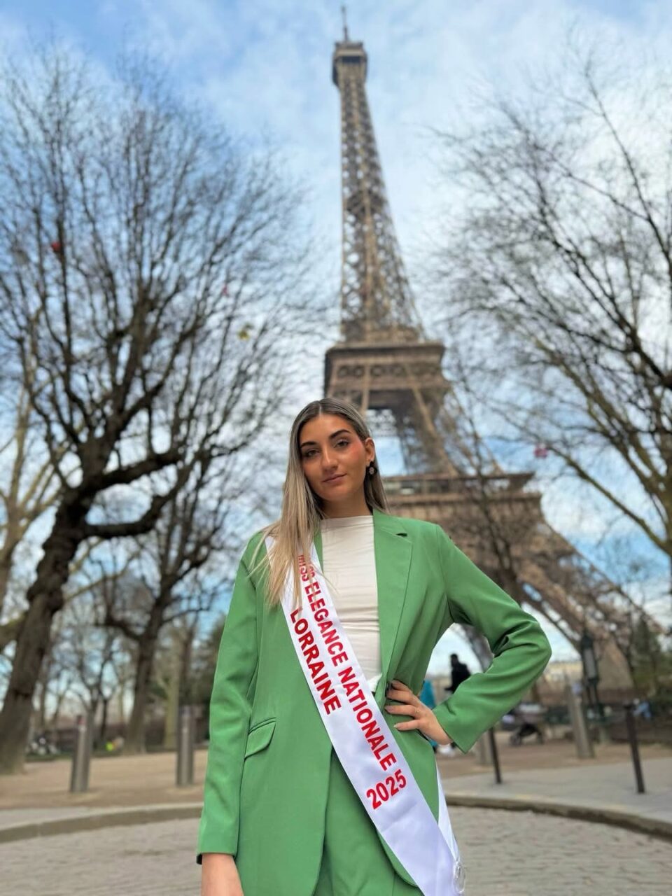 Carla Mastrorillo en veste verte et écharpe de Miss, devant la tour Eiffel