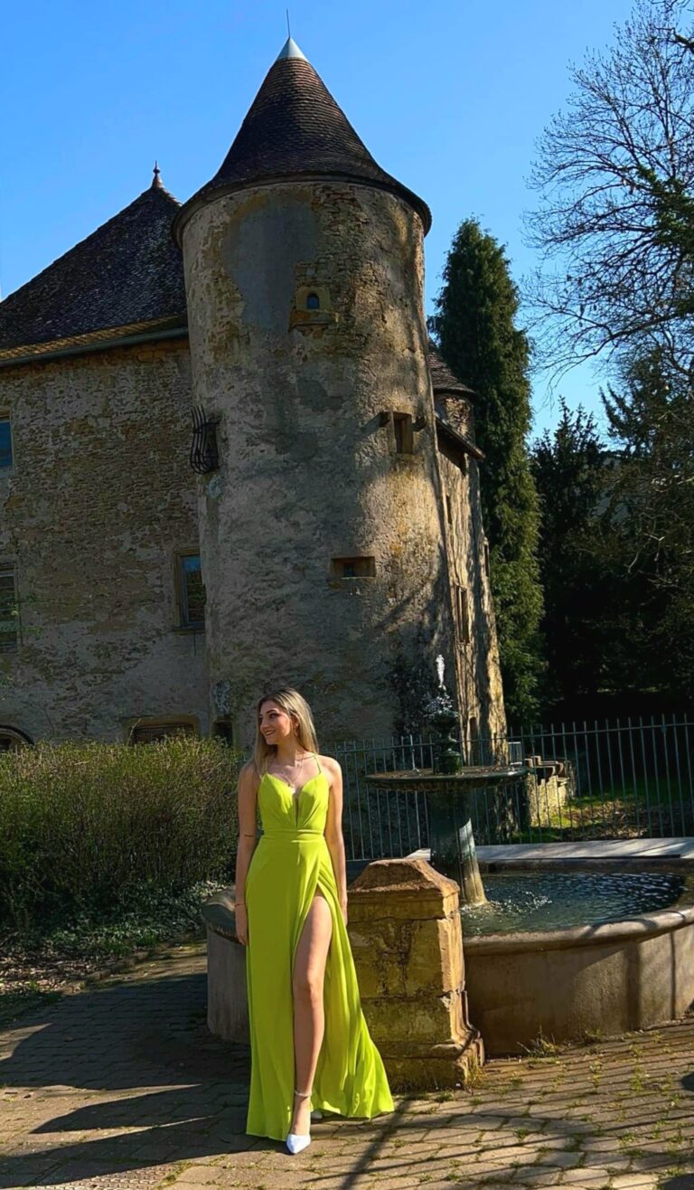 Carla Mastrorillo en robe longue vert anis, devant une tour ancienne