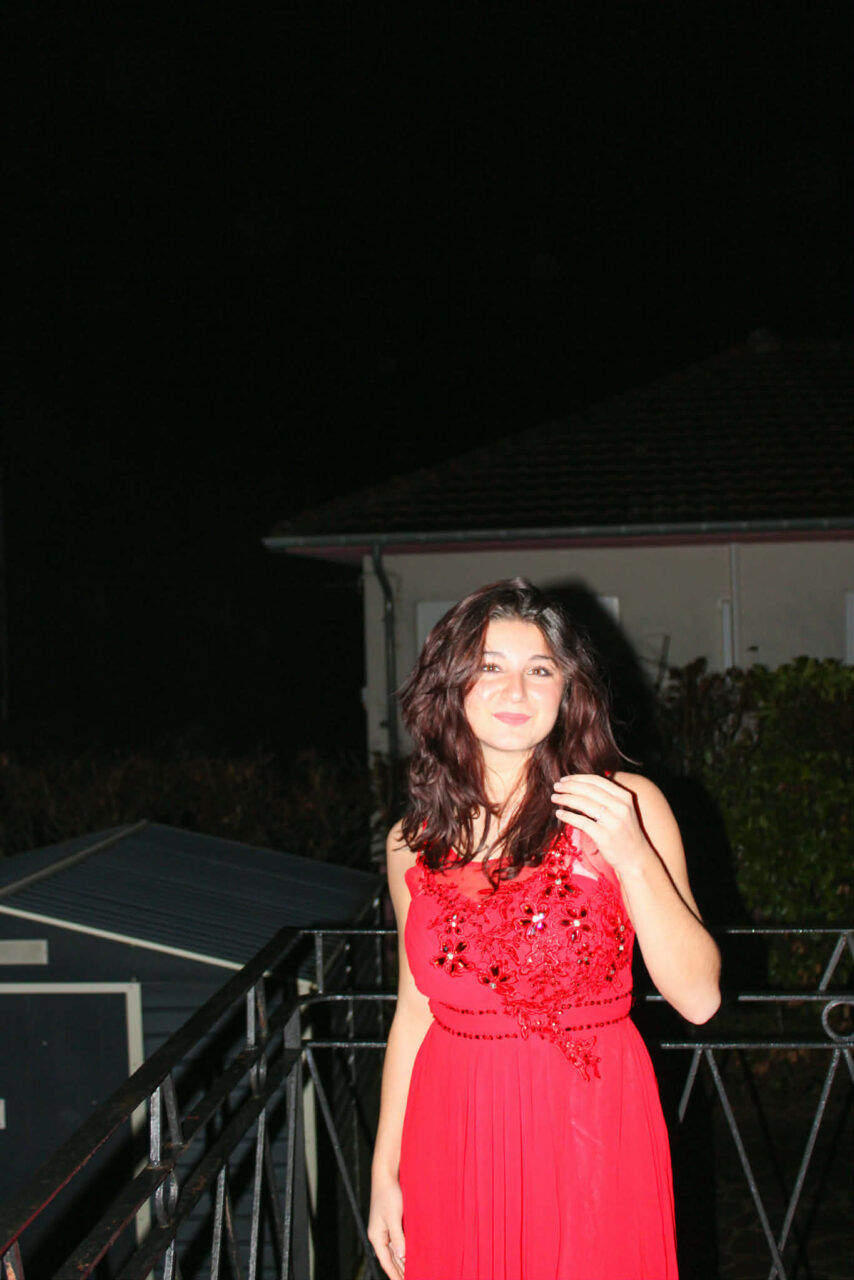 Maë Rosato, robe rouge, la main dans les cheveux