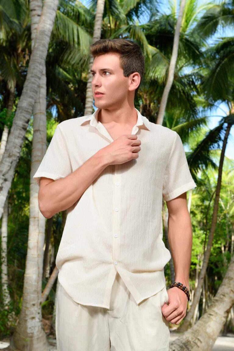 Timothy Legros en chemise de lin écrue, sous les palmiers