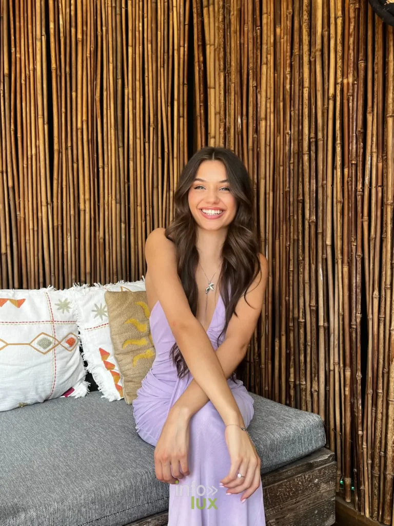 Elisa en robe lilas, assise devant un rideau de bambou
