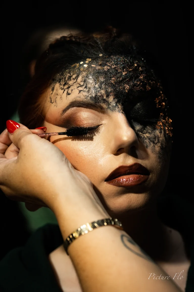 Auftragen der Wimperntusche; die schwarze Masse bedeckt bereits die Stirn