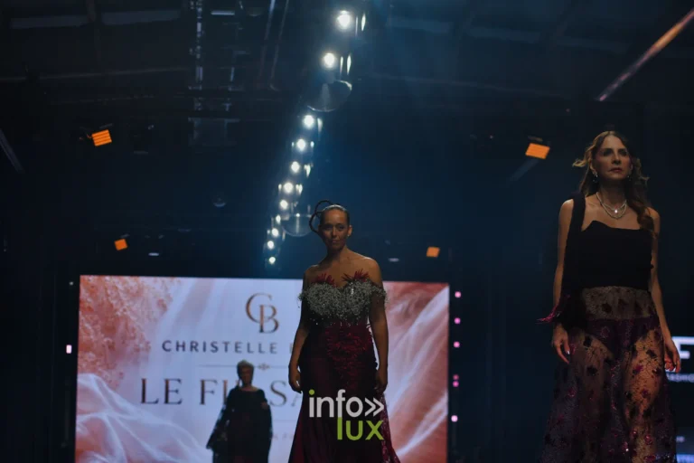 Robe de gypsophile et satin bordeaux et jupe en tulle noir brodé, devant l’écran de la collection, collection « Le Fil Sacré » de Christelle Bukasa, Lux Fashion Week 2026, Arlon