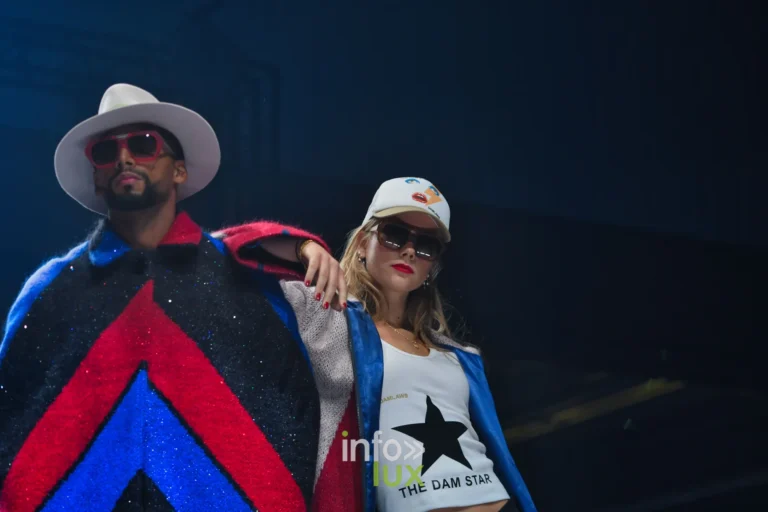 Cape noire à chevrons rouge et bleu et t-shirt blanc imprimé « THE DAM STAR » avec une étoile noire — Damlaws, « The Dam Star », Lux Fashion Week 2026, Arlon