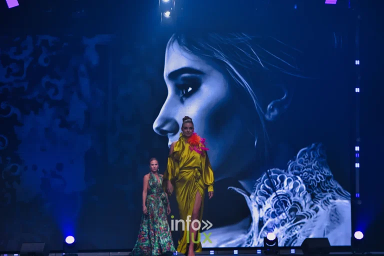 Robe en satin jaune et robe longue à imprimé végétal vert, devant un grand portrait de profil projeté à l’écran, collection « Meraki bloom » d’Hélène Guiot, Lux Fashion Week 2026, Arlon