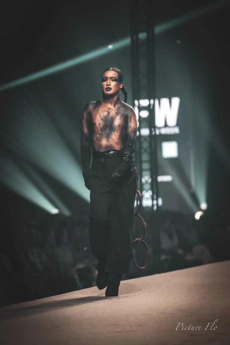 Sur le podium, il avance vers le public, devant l’écran LFW