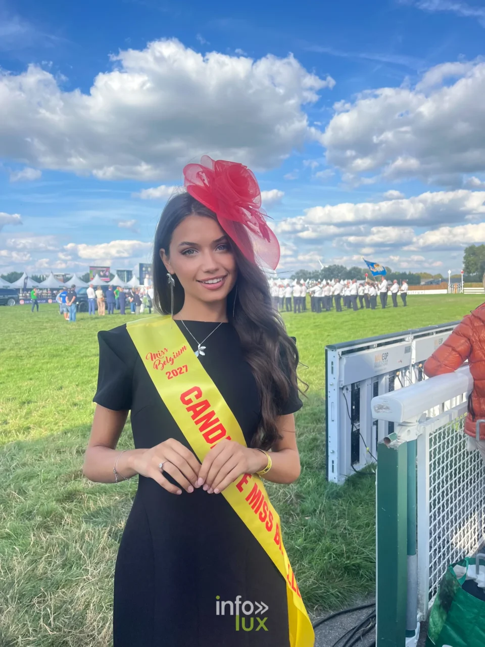 Elisa en écharpe de candidate Miss Belgique 2027 et bibi rouge, lors d’une sortie